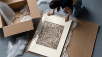 Adam laboring with skeleton Death figure framed print being unpacked from protective bubble wrap and a box