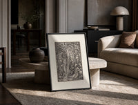 Adam and Eve in Eden print in a black frame leaning on a travertine table in a sunlit lounge