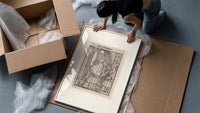 Death and clergyman woodcut scene framed print being unpacked from protective bubble wrap and a box