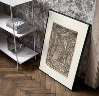 Death crowning enthroned king poster in a black frame leaning beside a shelf in a raw-plaster loft