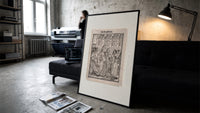 Death dancing with empress print in a slim black frame leaning on a dark sofa in a concrete print studio