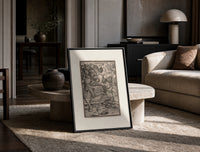 Death fighting armored nobleman print in a black frame leaning on a travertine table in a sunlit lounge