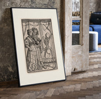 Death dancing with noble couple print in a black frame leaning beside a vintage door on parquet