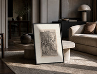Death leading a queen away print in a black frame leaning on a travertine table in a sunlit lounge