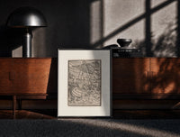 Black-framed Ship in stormy sea with figures print on a moody console with designer coffee-table books