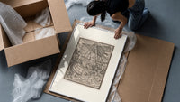 Ship in stormy sea with figures framed print being unpacked from protective bubble wrap and a box