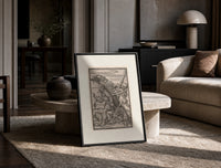 Peasant carrying load with Death skeleton print in a black frame leaning on a travertine table in a sunlit lounge