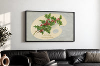 Holly Hearty Christmas Greetings print in a black frame above a black leather sofa on a white wall