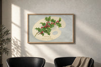 Holly Hearty Christmas Greetings print in an oak frame on a sunlit wall above two leather armchairs