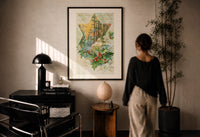 Holly With Every Good Wish print in a black frame on a sunlit plaster wall, a person looking on beside a mushroom lamp