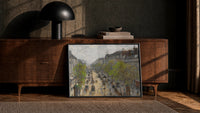 Parisian boulevard with carriages vintage art print print in a black frame leaning against a walnut console in lamplight
