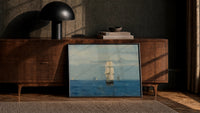 tall ship sailing open sea vintage art print print in a black frame leaning against a walnut console in lamplight