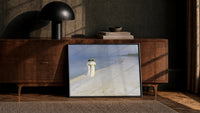 two women in white walking a beach at dusk vintage art print print in a black frame leaning against a walnut console in…