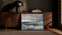 storm waves crashing on a rocky shore vintage art print print in a black frame leaning against a walnut console in lamplight