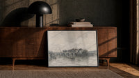 Parisian bridge and riverside architecture vintage art print print in a black frame leaning against a walnut console in…