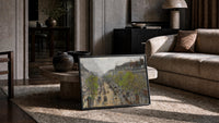 Parisian boulevard with carriages vintage art print print in a slim black frame leaning on a travertine coffee table