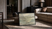 stormy grey-green seascape with breaking waves vintage art print print in a slim black frame leaning on a travertine…