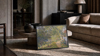 sun-dappled garden path beside a cottage vintage art print print in a slim black frame leaning on a travertine coffee table