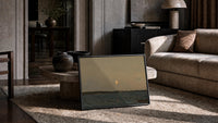 moonrise over calm sea vintage art print print in a slim black frame leaning on a travertine coffee table