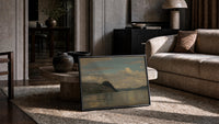 fjord/lake with dramatic clouds vintage art print print in a slim black frame leaning on a travertine coffee table