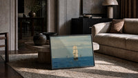 tall ship sailing open sea vintage art print print in a slim black frame leaning on a travertine coffee table