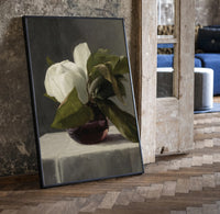 white peony in dark glass vase vintage art print print in a black frame leaning beside a vintage door on parquet