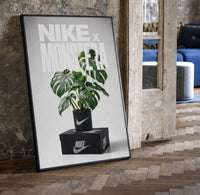 Nike Monstera Sneaker framed poster print in a black frame leaning beside a vintage door on parquet