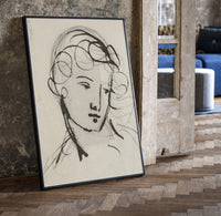 woman's head in flowing contour lines vintage art print print in a black frame leaning beside a vintage door on parquet