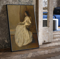 seated woman in white dress vintage art print print in a black frame leaning beside a vintage door on parquet