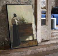 woman reading at a dresser in a quiet interior vintage art print print in a black frame leaning beside a vintage door on…