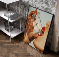 Luxury Fragrance Portrait framed poster poster in a black frame leaning beside a shelf in a raw-plaster loft