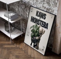 KAWS Companion Monstera Nike framed poster poster in a black frame leaning beside a shelf in a raw-plaster loft