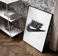 Nike Just Do It Swoosh framed poster poster in a black frame leaning beside a shelf in a raw-plaster loft
