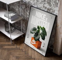 Nike Monstera Sneaker Box Green framed poster poster in a black frame leaning beside a shelf in a raw-plaster loft