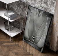 Chanel CC Necklace Black & White framed poster poster in a black frame leaning beside a shelf in a raw-plaster loft