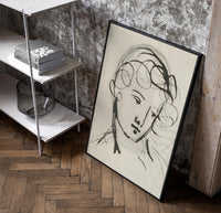 woman's head in flowing contour lines vintage art print poster in a black frame leaning beside a shelf in a raw-plaster loft