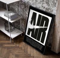 Nike Air History framed poster poster in a black frame leaning beside a shelf in a raw-plaster loft