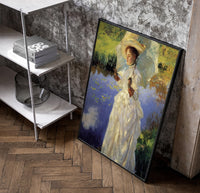 woman with a parasol beside a lily pond vintage art print poster in a black frame leaning beside a shelf in a raw-plaster…