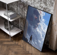 Attack on Titan Colossal framed poster poster in a black frame leaning beside a shelf in a raw-plaster loft