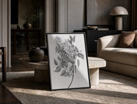 flowering lilac branch vintage art print print in a black frame leaning on a travertine table in a sunlit lounge