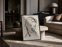woman's head in flowing contour lines vintage art print print in a black frame leaning on a travertine table in a sunlit…