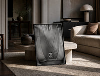 Chanel CC Necklace Black & White framed poster print in a black frame leaning on a travertine table in a sunlit lounge