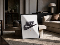 Nike Just Do It Swoosh framed poster print in a black frame leaning on a travertine table in a sunlit lounge