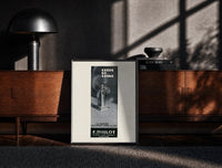 Black-framed Crepe de Chine Millot Parfum print on the floor in front of a dark wooden console