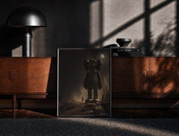 Black-framed KAWS Companion Desert Moon Monochrome print on the floor in front of a dark wooden console