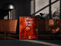 Black-framed Off the Beaten Path KAWS-Inspired Red Plush print on the floor in front of a dark wooden console