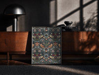 Black-framed William Morris Strawberry Thief print on the floor in front of a dark wooden console