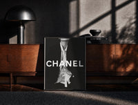 Black-framed Chanel Black & White Luxury print on the floor in front of a dark wooden console