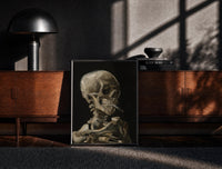 Black-framed skeleton smoking a cigarette vintage art print print on a moody console with designer coffee-table books
