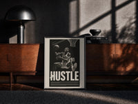 Black-framed Dennis Rodman Hustle Basketball print on the floor in front of a dark wooden console